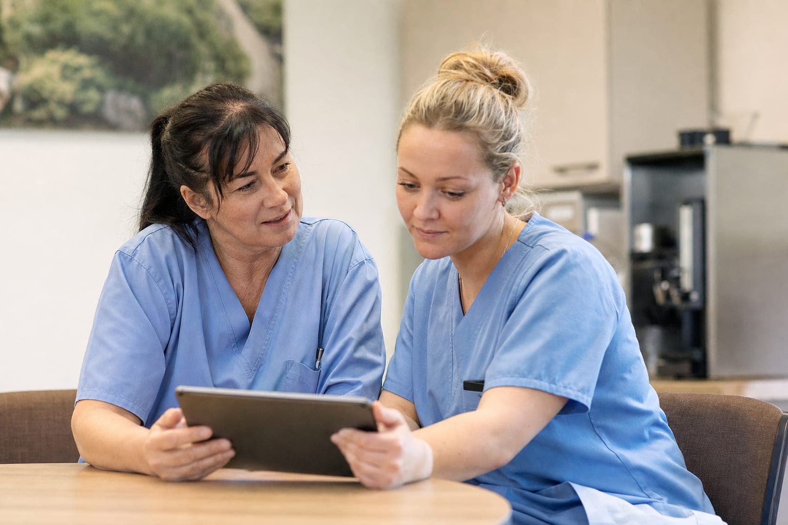 Betriebsinhaber und neue Fachkraft am Tablet in der Werkstatt